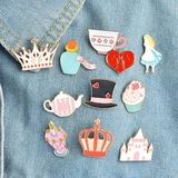 Detailed enamel pins featuring cartoon castle and tea party motifs on denim fabric