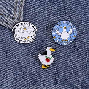 Detailed macro view of three cute duck enamel pins on denim fabric texture background