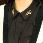 Vue détaillée des broches de col en forme de bois dorés sur chemise noire