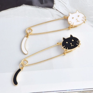 Détail de broches épingles chat avec queues pendantes en émail noir et blanc élégant