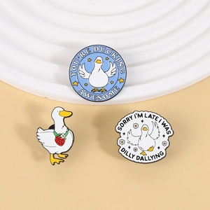Close-up of three cute enamel duck pins with creative slogans and strawberry charm