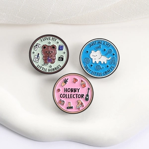 Set of three round enamel animal pins featuring a bear, cat, and hobby-themed illustrations