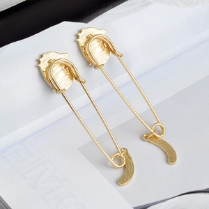Détail de boucles d'oreilles épingle dorées avec profils gaufrés sur magazine