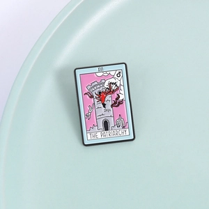 Macro shot of a rectangular tarot enamel pin featuring the XVI The Patriarchy design