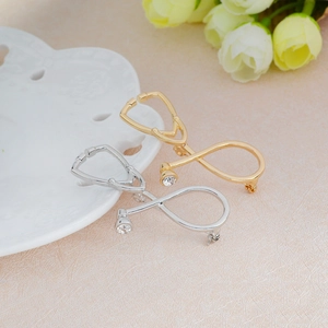 Broches stéthoscope or et argent avec strass étincelants sur fond texturé élégant