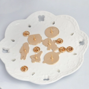 Close-up of gold-plated metal pin backs and butterfly clasps on a white tray