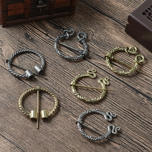 Détails de broches vikings vintage en argent et bronze antiques sur fond de bois