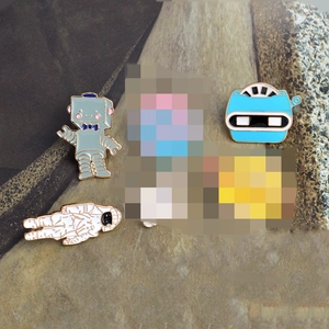 Cartoon enamel pin set featuring astronaut and robot designs on a textured background