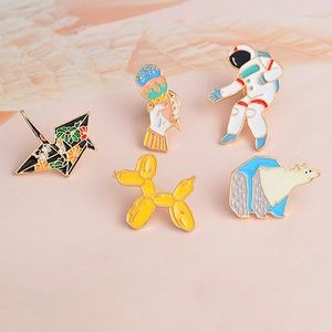 Dettaglio di spille in smalto colorato con astronauta, gru di carta e cane palloncino
