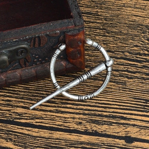 Détail d'une broche viking argentée avec motifs celtiques sur fond de bois rustique