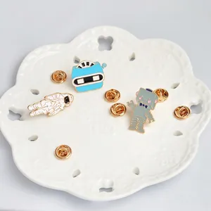 Cartoon enamel brooch set with astronaut and robot designs on a white lace plate