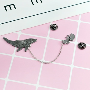 Detail view of the silver whale brooch back with dual pins and connecting chain
