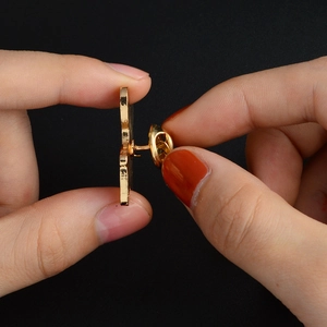 Detail of a metal enamel pin back featuring a gold-plated needle and butterfly clutch
