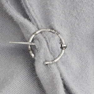 Vue détaillée d'une broche viking vintage en argent fixée sur un tricot bleu clair