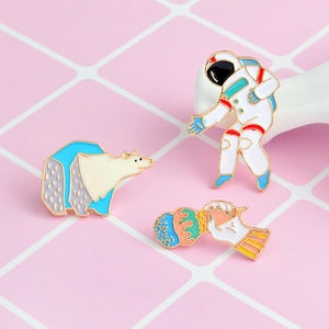 Dettaglio di spille smaltate colorate con astronauta e orso polare su griglia rosa