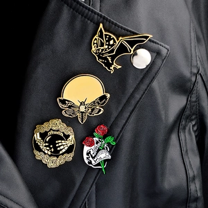 Details von vier gotischen Emaille-Pins mit Fledermäusen und Totenköpfen auf Lederjacke