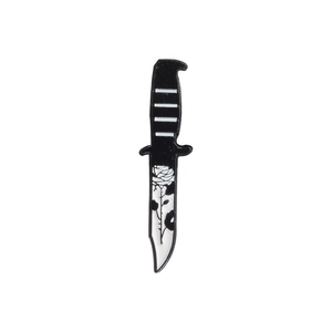 Detailed view of punk style black and white enamel dagger brooch with rose pattern