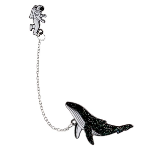 Detailed close-up of astronaut and whale enamel pins connected by a silver chain