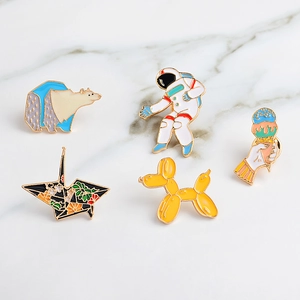 Dettaglio di spille in smalto colorato con design di astronauta e cane palloncino