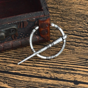 Détail macro d'une broche Viking vintage en alliage argenté sur un écrin à bijoux en bois