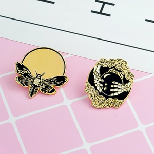 Detailaufnahme von Gothic-Emaille-Pins mit Totenkopfmotte und Skeletthänden mit Rosen