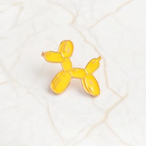 Macro di una spilla in smalto a forma di cane palloncino giallo con bordi in metallo oro