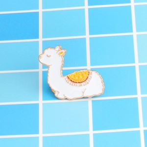 Détail de la broche lama en émail blanc avec bords dorés et selle fleurie colorée