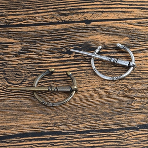 Détail de broches fibules vikings vintage en argent antique et bronze sur bois sombre