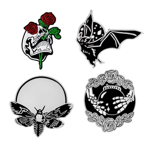 Detailansicht von vier Gothic-Emaille-Pins mit Totenkopf, Fledermaus, Motte und Blumen