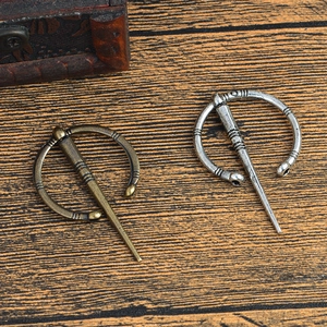 Détail de broches fibules viking vintage en bronze et argent sur fond de bois