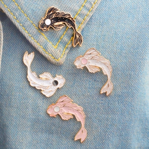 Cute koi fish enamel pins in black and white set on blue denim fabric background