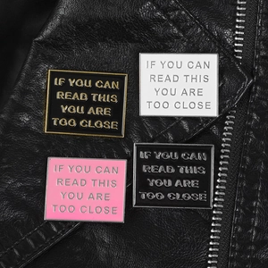 Detail of four enamel rectangular pins with text IF YOU CAN READ THIS YOU ARE TOO CLOSE