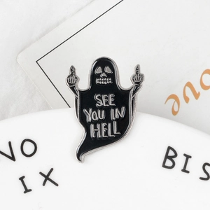Makroaufnahme der schwarzen Geister-Emaille-Nadel mit SEE YOU IN HELL Text und Geste