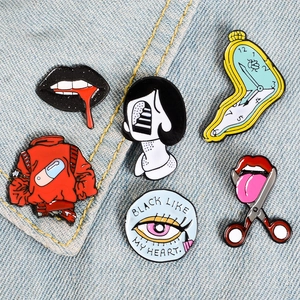 Close-up of creative enamel pins including melting clock and heart eye on denim fabric