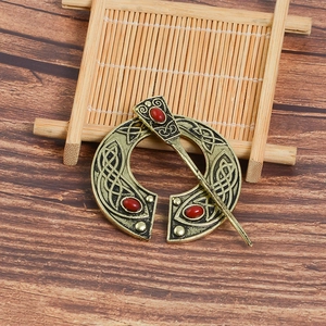 Detail of vintage Celtic viking brooch with red gemstones and bronze knotwork pattern