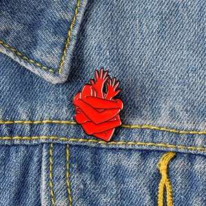 Broche créative en émail rouge en forme de cœur sur une veste en jean