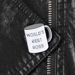 Detail of a teacup enamel pin with WORLD'S BEST BOSS text pinned on a leather jacket