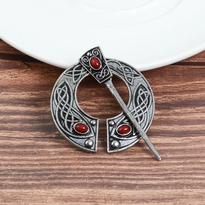 Detailed macro of antique silver Viking brooch with Celtic knots and red gemstone inlays