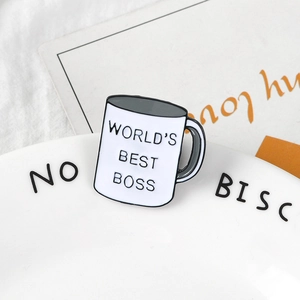 Detailed view of World's Best Boss white enamel pin on a decorative dish background