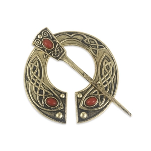 Detail of vintage Celtic penannular brooch with bronze metal and red cabochon stones