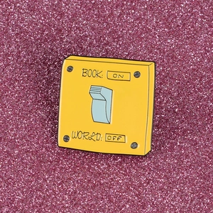 Yellow enamel switch brooch with BOOK ON text on purple glitter background