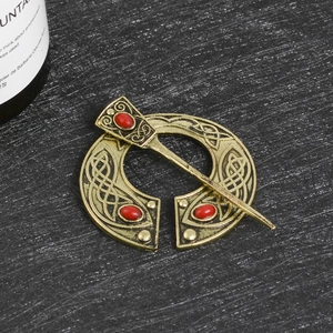 Antique gold Celtic penannular brooch with red ruby beads and intricate knotwork patterns