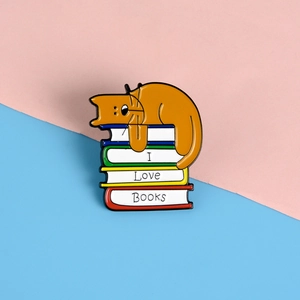 Detail einer Emaille-Anstecknadel mit schlafender Katze auf Büchern mit I LOVE BOOKS
