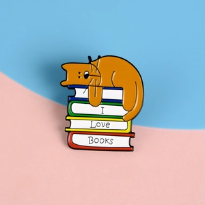 Detail einer Emaille-Anstecknadel mit schlafender Katze auf bunten Büchern und Text