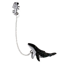 Detailed view of astronaut and whale enamel brooch pins connected by a silver chain