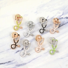 Flat lay of stethoscope brooches in gold, silver and rose gold on white marble