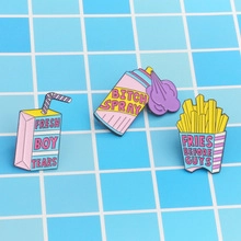 Close-up of three enamel pins with slogans Fresh Boy Tears Bitch Spray and Fries Before Guys