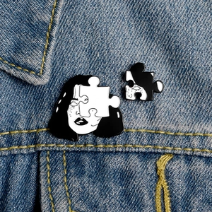 Close-up of enamel creative woman face puzzle brooch set on blue denim jacket collar