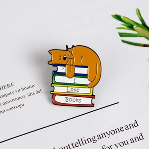 Kreative Emaille-Anstecknadel mit einer orangefarbenen Katze, die auf I Love Books Büchern schläft