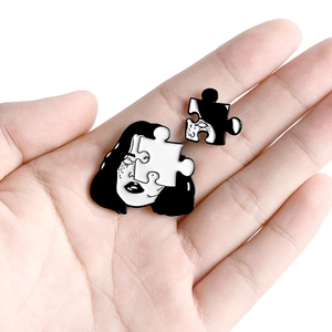 Artistic enamel puzzle piece portrait pin set in monochrome finish shown on hand